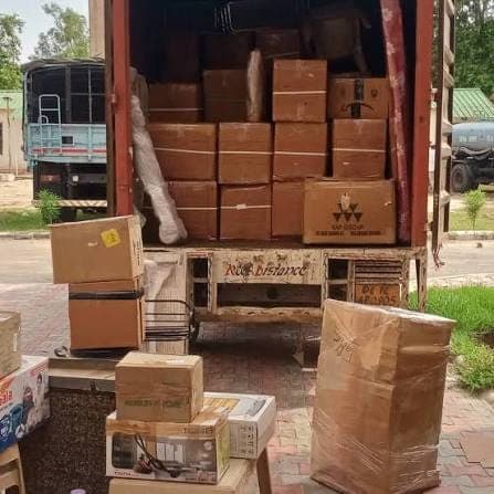 A Dev Packers & Movers truck loaded with labelled cartons, wrapped furniture and boxed appliances, stacked to the roof